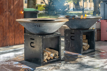 Wood-burning grill with a metal plate for frying meat and vegetables with a flame of fire. Street...