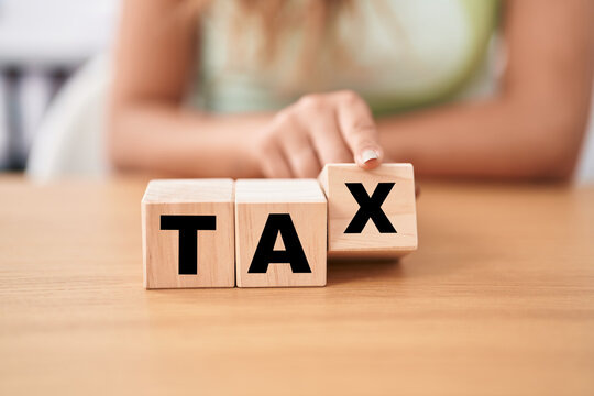 Young woman holding cubes with tax word on the table