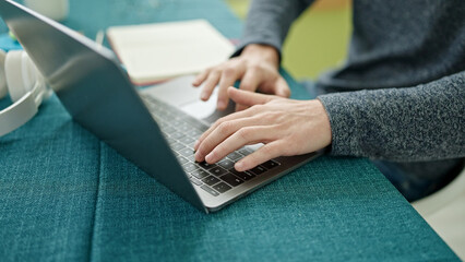 Young hispanic man using laptop sitting on the table at dinning room