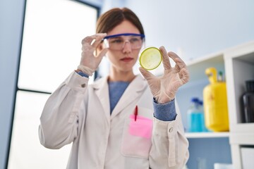 Naklejka premium Young blonde woman scientist looking sample with serious expression at laboratory