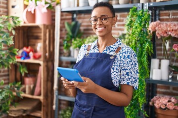African american woman florist smiling confident using touchpad at florist