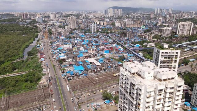 Aerial view of Mumbai city over Dharavi which is Asia's largest slum with local railway trains passing as city scape of Mumbai is revealed. Drone shot of Indian city over slum area with railways train