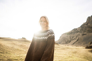 A girl in fashion clothes poses in mountains an Icelandic sweater