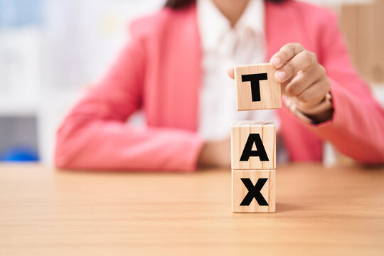 Business woman holding cubes with tax word on the table