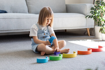 A cute girl is playing an educational game with a wooden rainbow. child development 