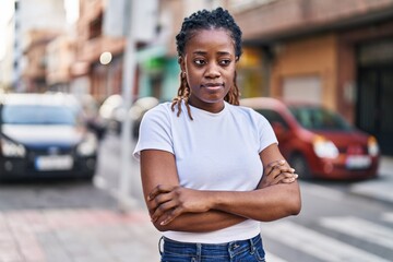 African american woman standing with serious expression and arms crossed gesture at street