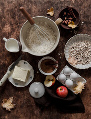 Baking background. Baking ingredients - flour, butter, apples, cinnamon, eggs, cane sugar, nuts - wooden background, top view