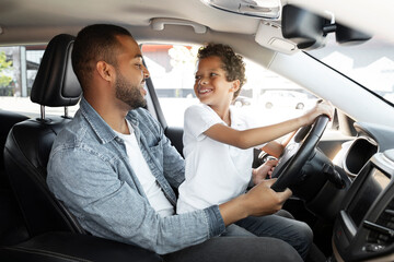 Happy loving black father and son driving car together