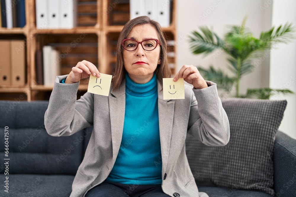 Wall mural middle age hispanic woman working on depression holding sad to happy emotion paper relaxed with seri