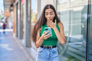 Young beautiful hispanic woman using smartphone with surprise expression at street