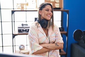 Young hispanic woman musician smiling confident standing with arms crossed gesture at music studio
