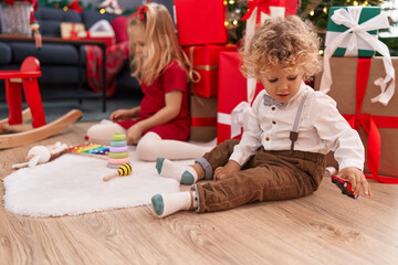 Adorable boy and girl playing with xylophone and car toy celebrating christmas at home