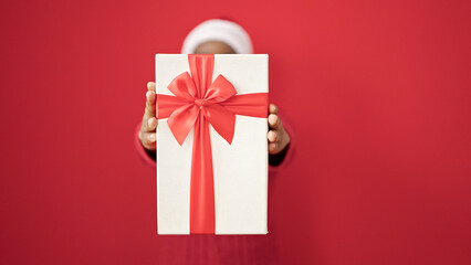 African american woman holding christmas gift over isolated red background