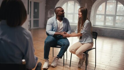Happy fit man with black skin color and short haircut together with his girlfriend with long hair thanks to psychologist for joint therapy. Happy endings to group therapy for couples