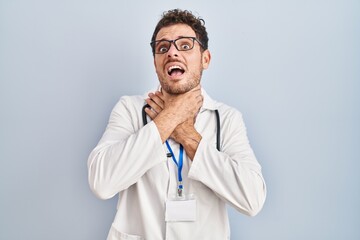 Young hispanic man wearing doctor uniform and stethoscope shouting and suffocate because painful...