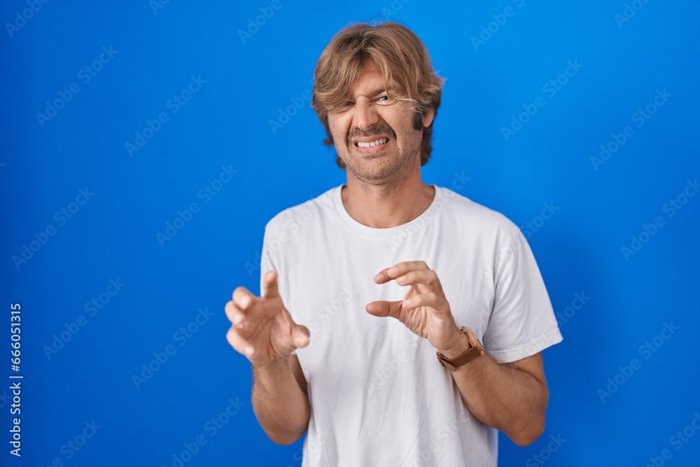 Canvas Prints middle age man standing over blue background disgusted expression, displeased and fearful doing disg