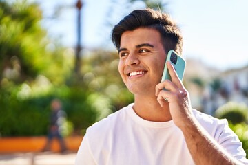 Young hispanic man smiling confident talking on the smartphone at park