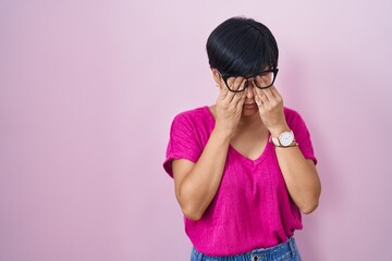 Young asian woman with short hair standing over pink background rubbing eyes for fatigue and headache, sleepy and tired expression. vision problem