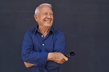 Senior grey-haired man smiling confident standing with arms crossed gesture over black background