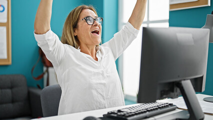 Middle age hispanic woman business worker using computer celebrating at the office