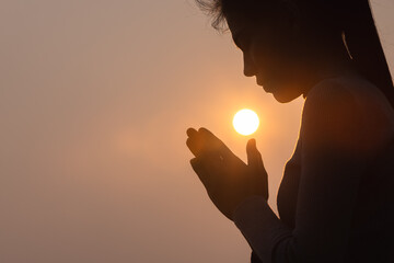 Silhouette of a woman paying respects and praying A symbol of gratitude to the Lord. - obrazy, fototapety, plakaty