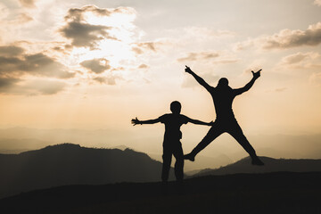 Silhouette of a man jumping with arms and legs spread as the sun sets. Success concept. journey for...