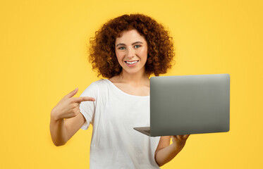 Smiling young caucasian woman student point finger at laptop, recommendation social networks