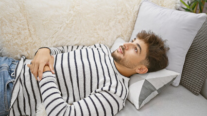 Young arab man lying on sofa at home