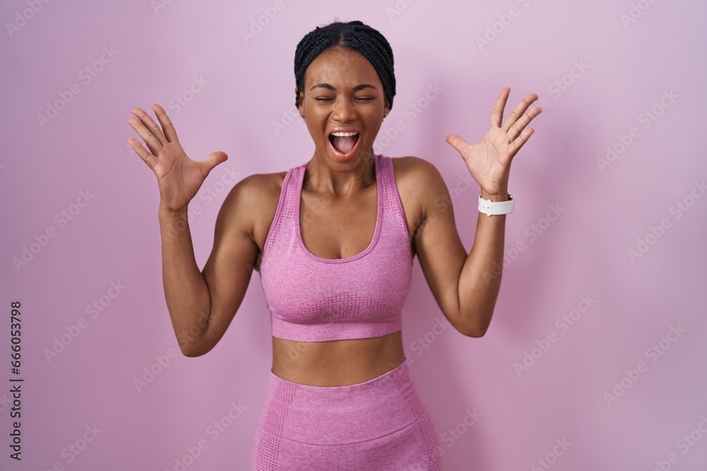 Poster african american woman with braids wearing sportswear over pink background celebrating mad and crazy