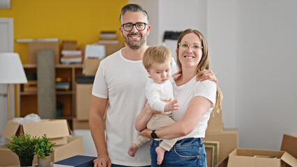 Family of mother, father and baby smiling together looking a the camera at new home