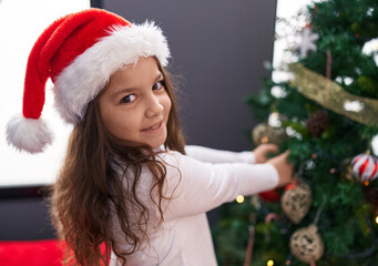 Adorable hispanic girl smiling confident decorating christmas tree at home