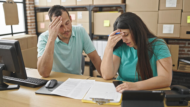 Two coworkers talking reading document worried at ecommerce office