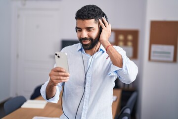 Young arab man business worker listening to music at office