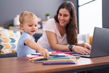 Fototapeta premium Mother and son drawing on notebook using laptop at home