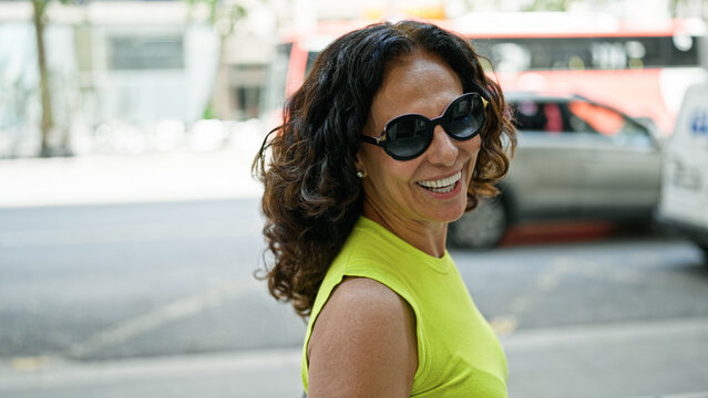 Middle age hispanic woman smiling confident wearing sunglasses at the street