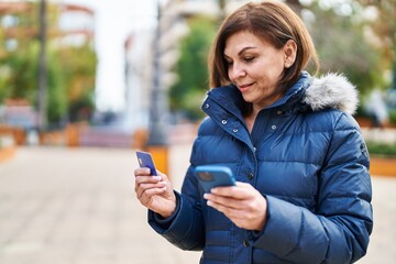 Middle age woman using smartphone and credit card at park