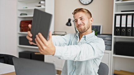 Naklejka na ściany i meble Young caucasian man business worker make selfie by touchpad at office