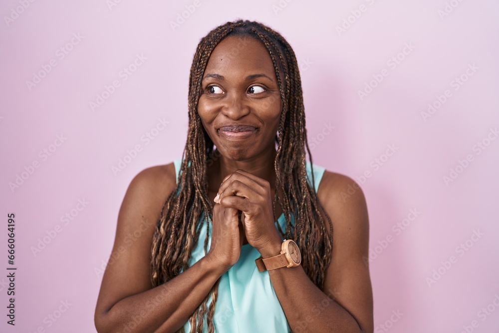 Poster African american woman standing over pink background laughing nervous and excited with hands on chin looking to the side