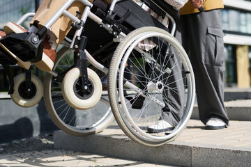 Close-up of man helping his friend with disability to go down the stairs outdoors