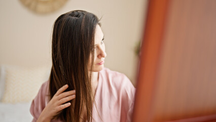 Young beautiful hispanic woman combing hair with hands at bedroom