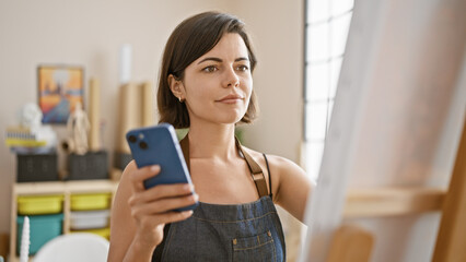 Fototapeta na wymiar Captivating portrait, beautiful young hispanic woman draw, fully engrossed in creative process of smartphone drawing at cozy art studio