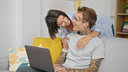 Beautiful couple hugging each other using laptop at home