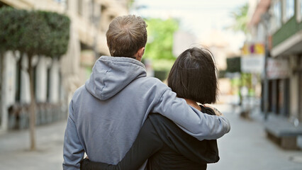 Beautiful couple hugging each other standing backwards at street