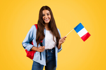 Cheerful caucasian young student woman, with France flag, combines patriotism with academia