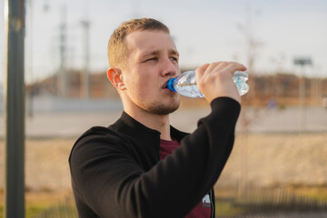 having a break on a sports groung during cross fit workout, man drinking water