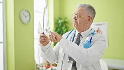 Middle age grey-haired man doctor looking xray at clinic