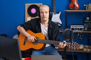 Young caucasian man musician playing classical guitar at music studio