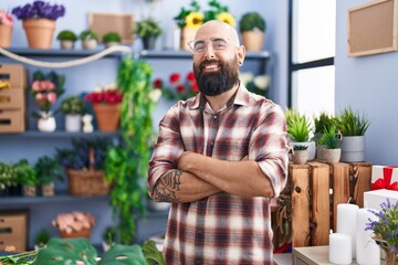 Young bald man florist smiling confident standing with arms crossed gesture at flower shop - obrazy, fototapety, plakaty