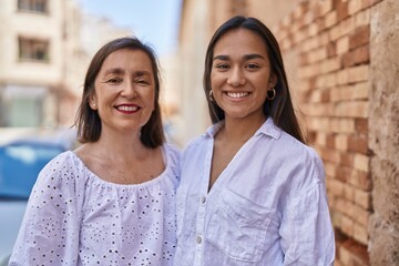 Fototapeta premium Two women mother and daughter smiling confident hugging each other at street