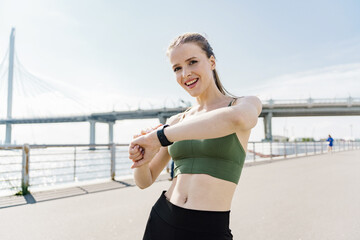 Uses a fitness watch. Fitness warm-up exercises muscle training and cardio endurance. A young athletic woman has a strong personality.